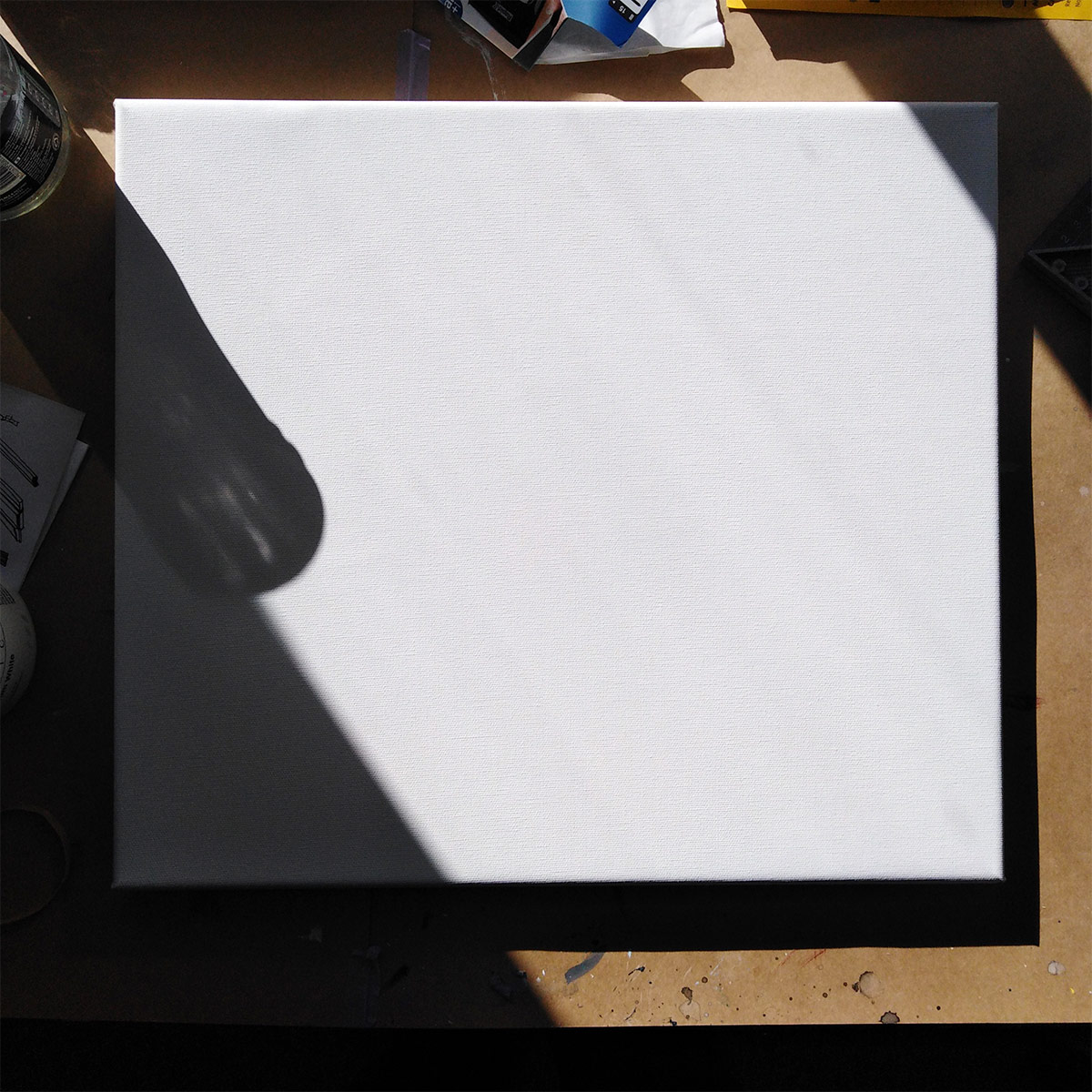 A white canvas lying on a sunlit table.